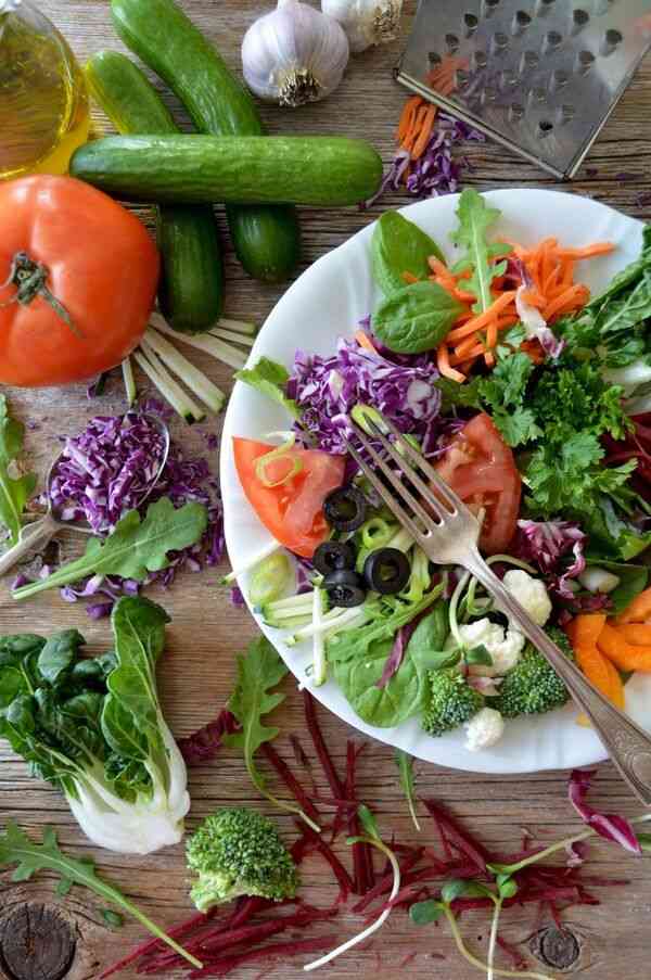 A square bowl filled with fresh vegetables and simple balanced ingredients